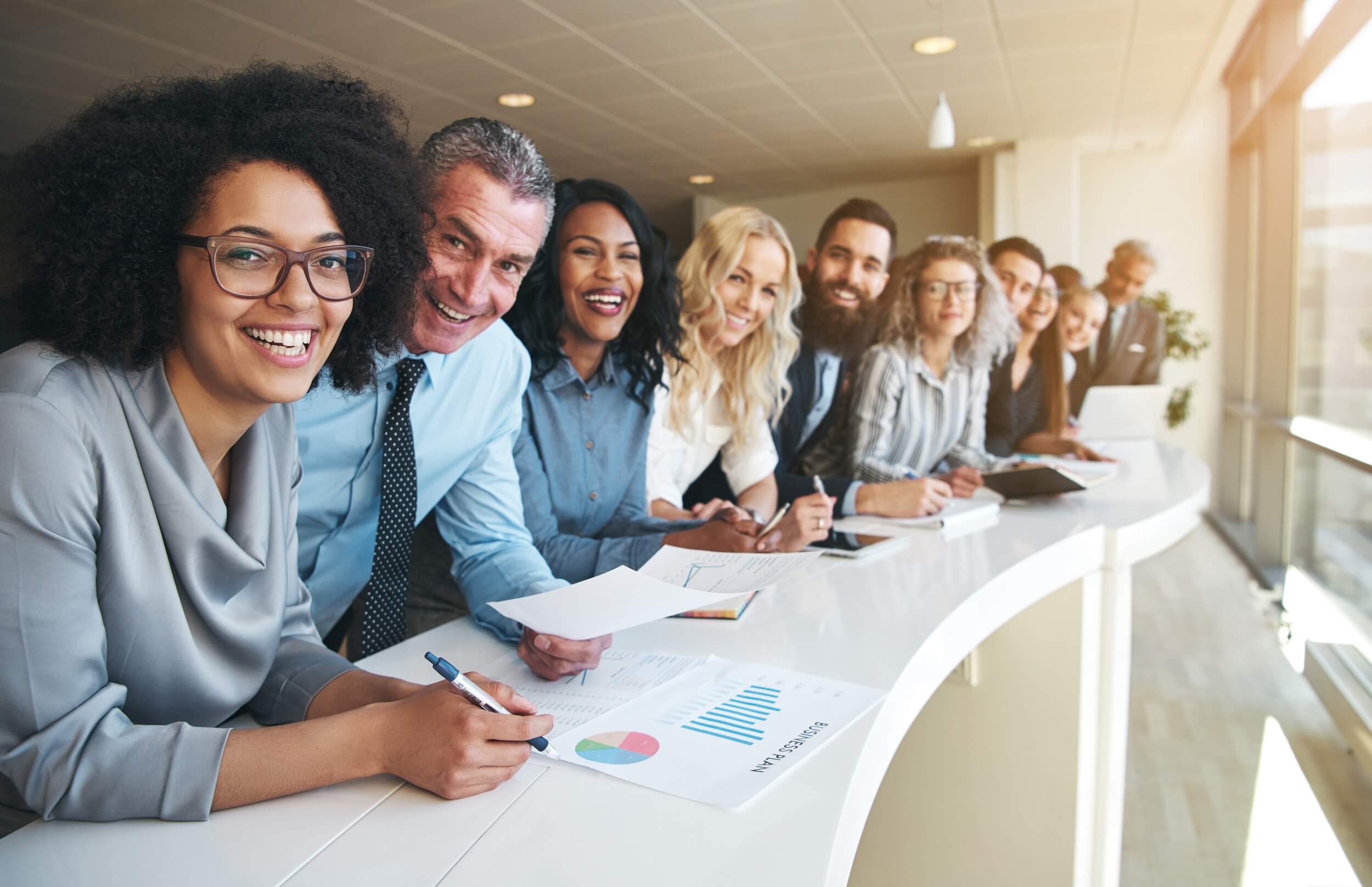 Row of smiling small business employees working together in a bright office