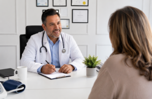A doctor in a white coat reviewing notes while talking with a patient during a Medicare Supplements consultation