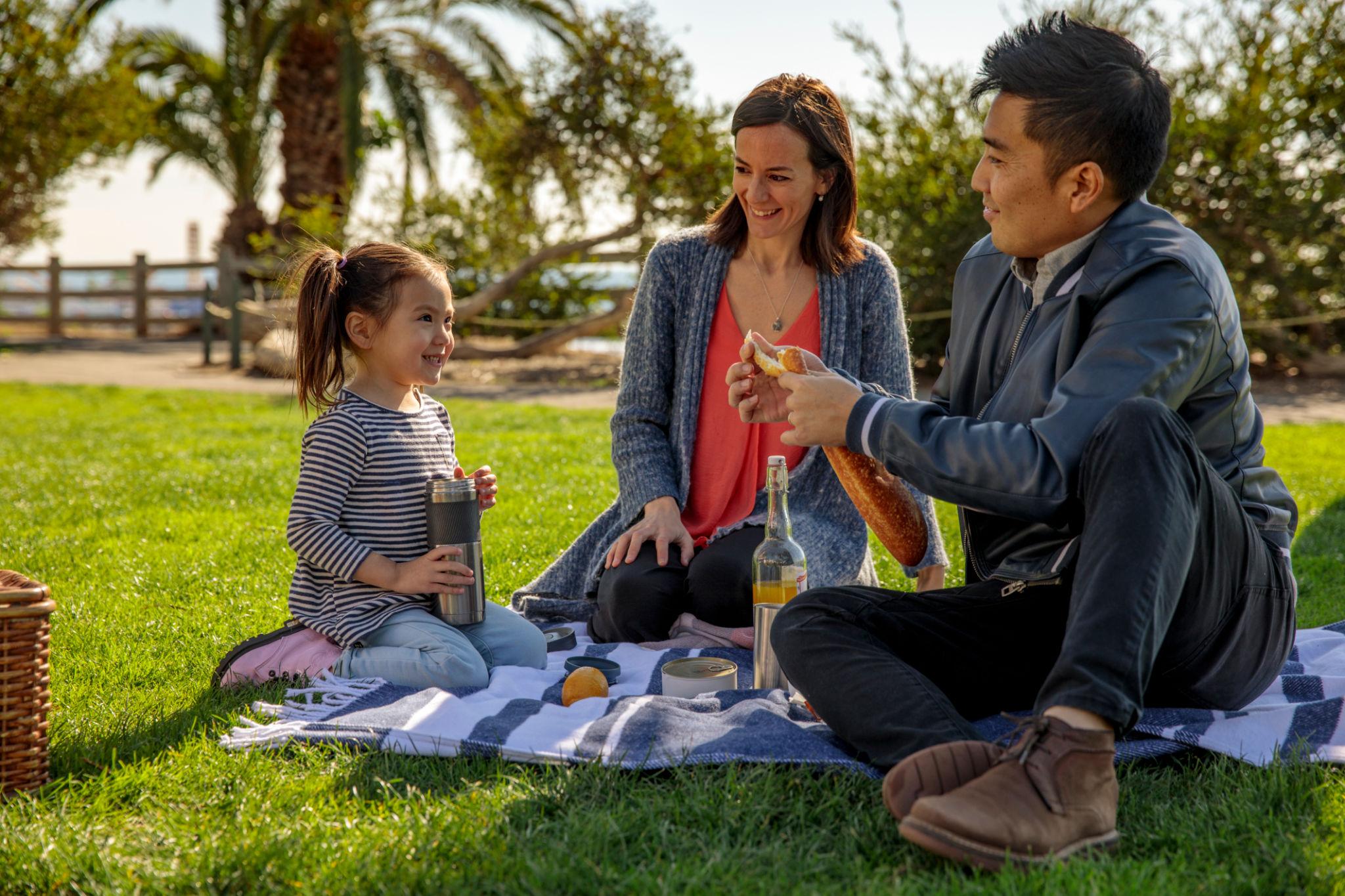 Young family having a picnic together in the park, representing life insurance for growing families